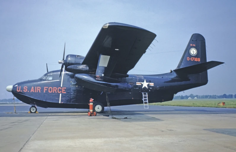 large black plane parked on concrete with ladder in the back