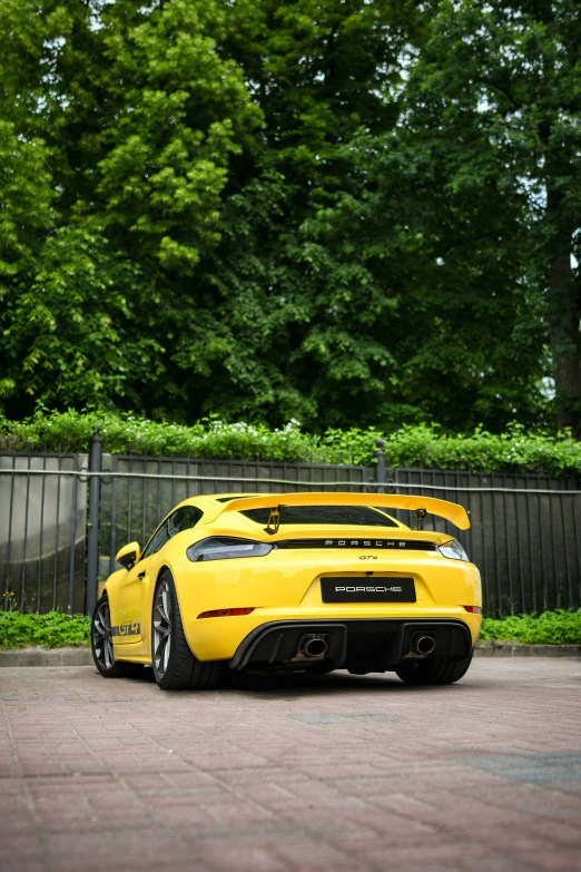 a yellow sports car parked next to a black fence