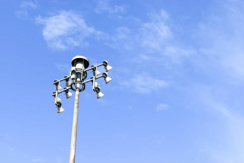 a tall metal pole topped with traffic lights under a blue sky