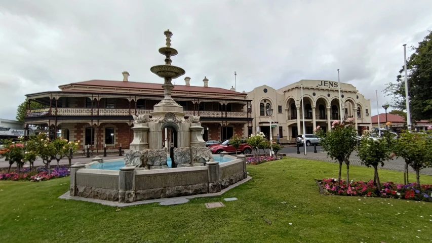 a courtyard fountain near a building on a cloudy day