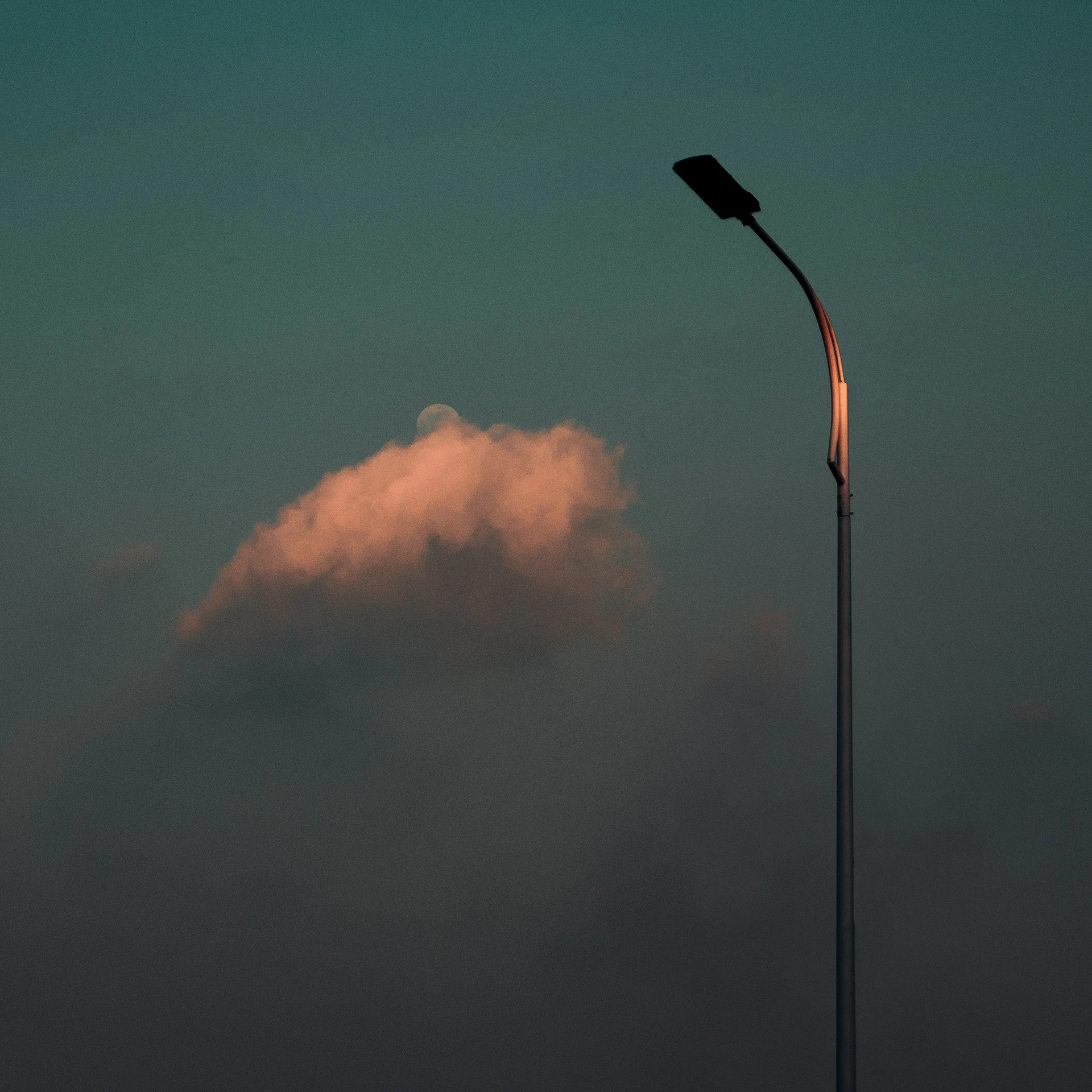 a street light sitting next to a cloudy sky