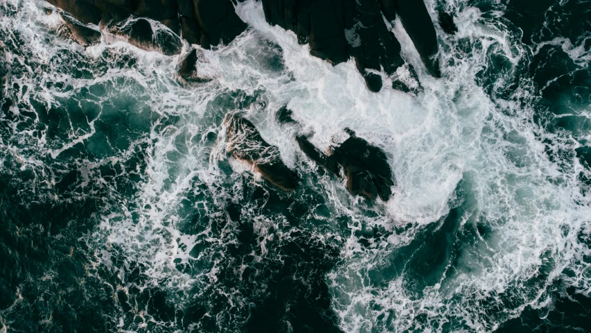 the view looking down at some waves crashing on some rocks