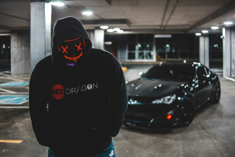 a hooded man standing in a parking garage