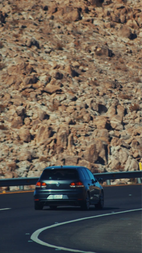 the back of a car on the side of the road near a mountain