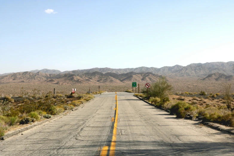 a road through a mountainous area has yellow lines on it