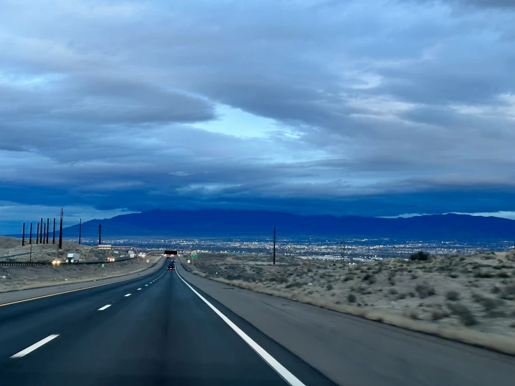 an empty highway with blue skies above mountains and plains