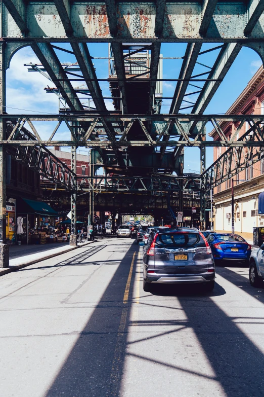 cars parked on the side of a street below a bridge