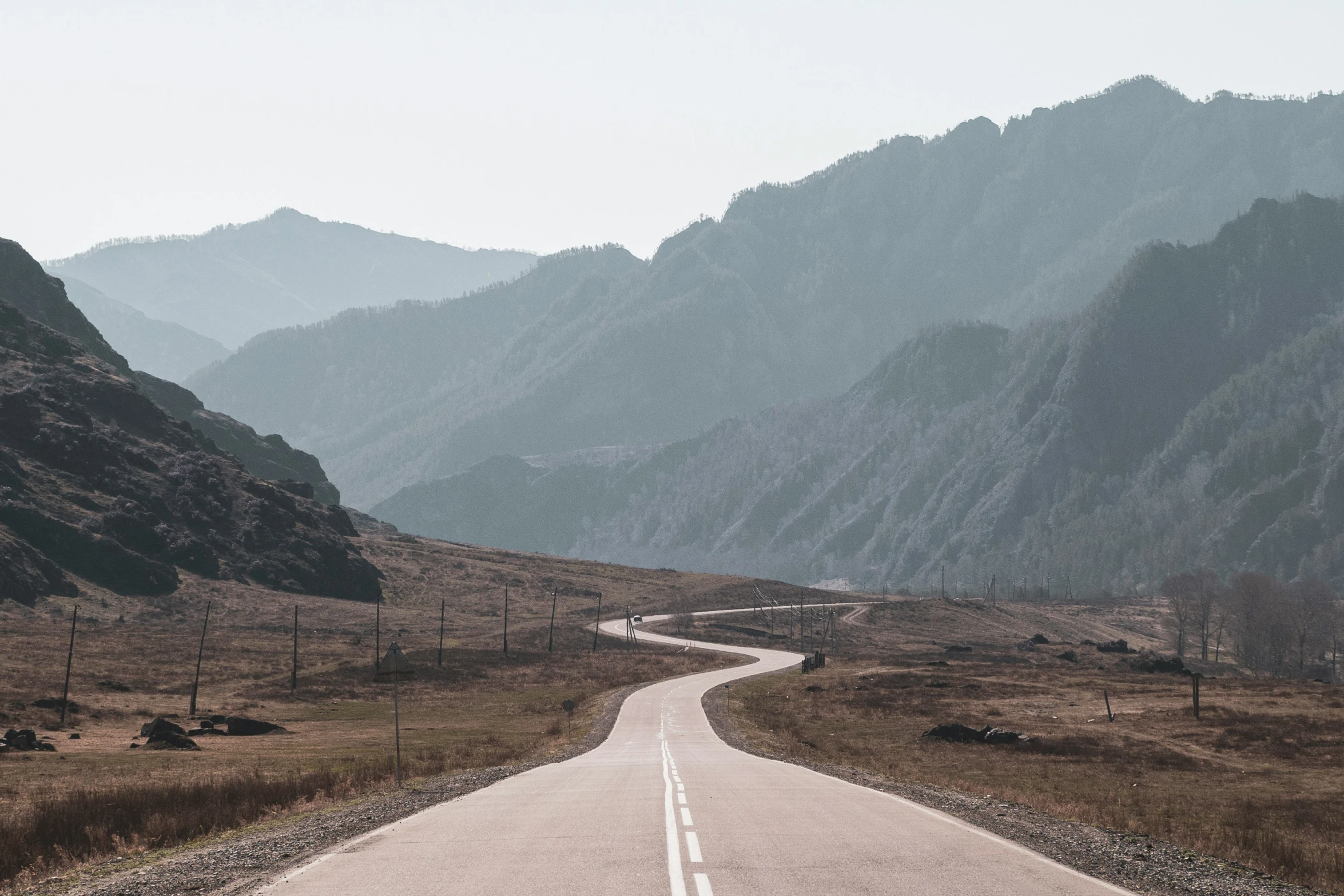 an empty road in the middle of some mountains