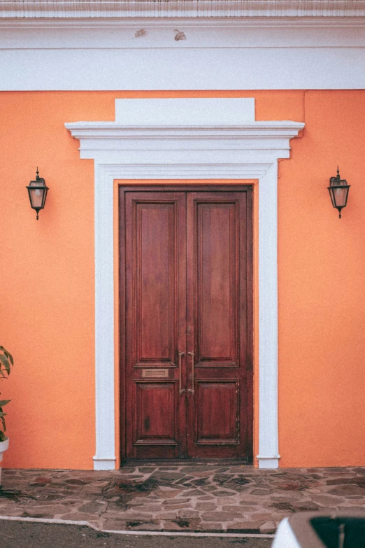 a wood double door on an orange wall with white columns