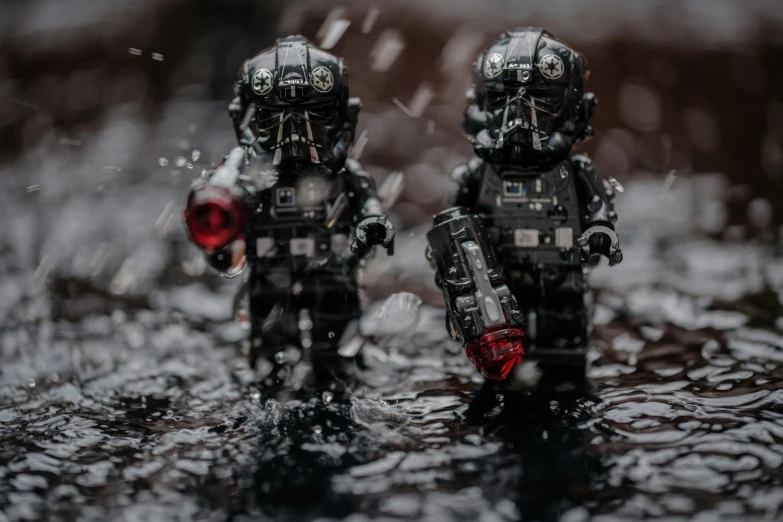 two small soldiers holding red umbrellas in water