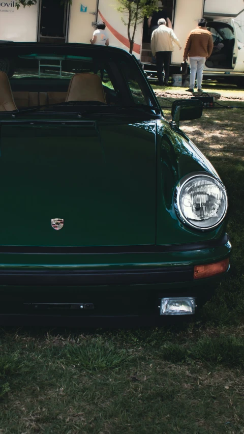 a green porsche sports car sits in the grass