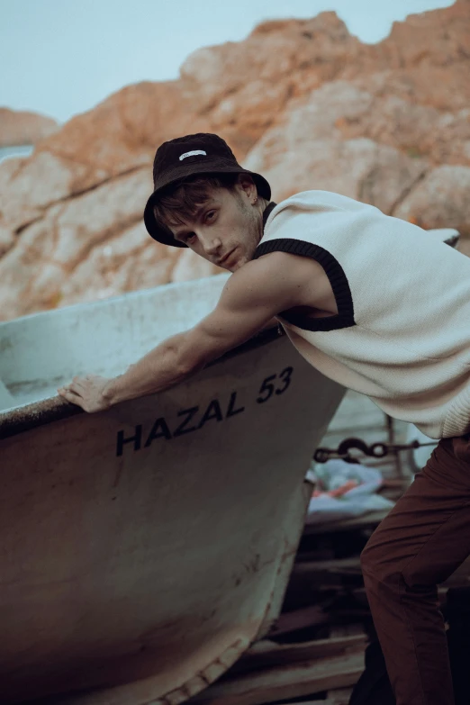 a young man in a hat leans over a boat