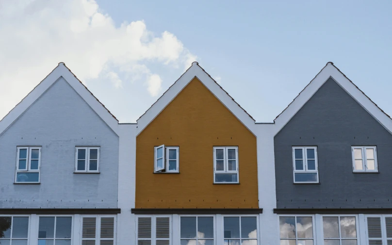 three houses in rows and each different color with windows on them