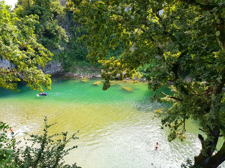 a small river surrounded by trees and people in boats