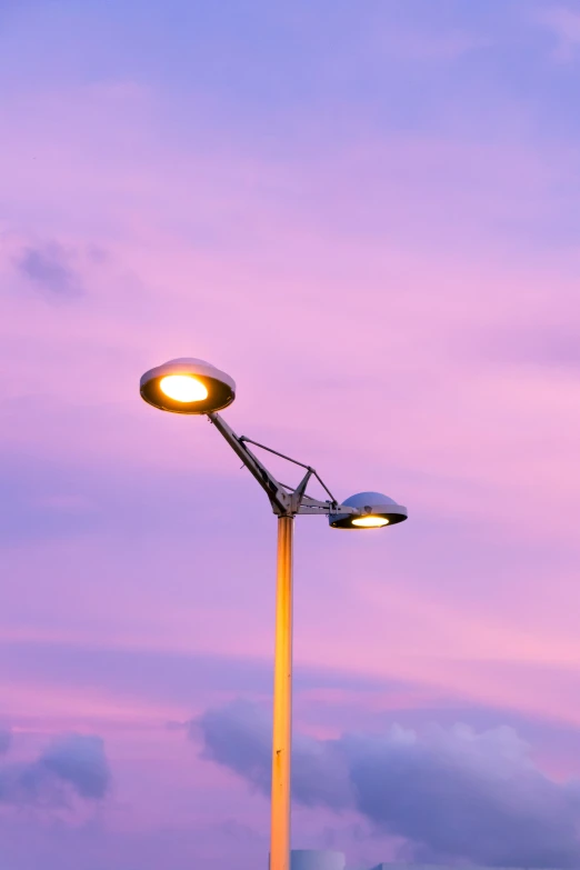 a lamp on the sidewalk near some clouds