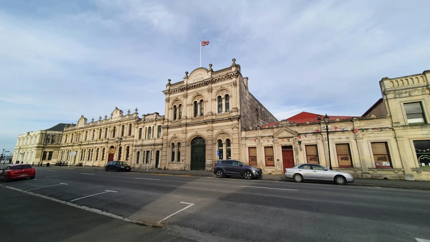 two identical cars parked in front of two old buildings