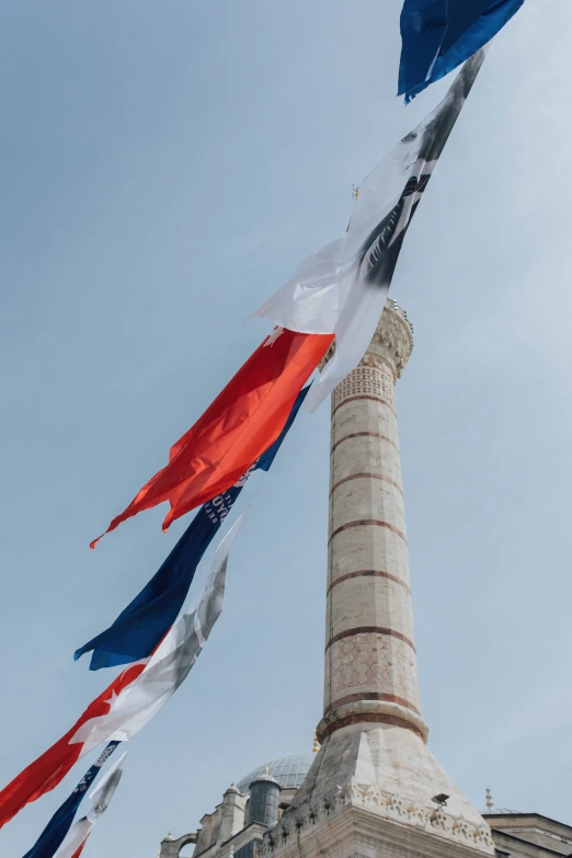 several flags flying in the wind next to a monument