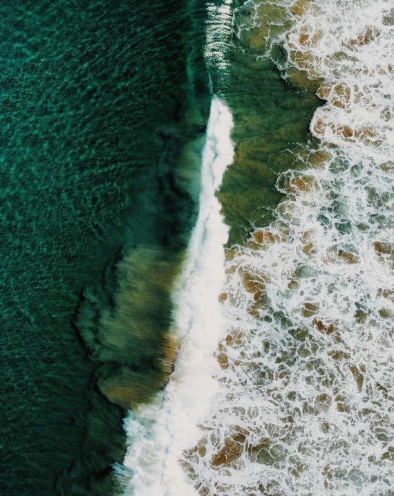 aerial view of a wave coming towards an ocean beach