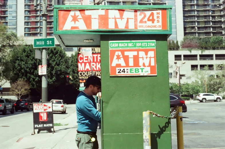 a man stands in front of an atm machine