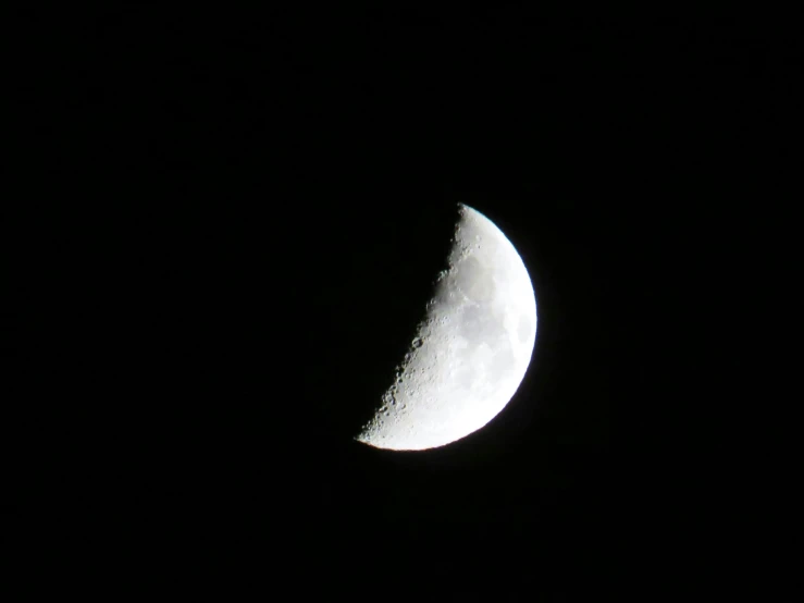 a half moon in the sky with dark skies