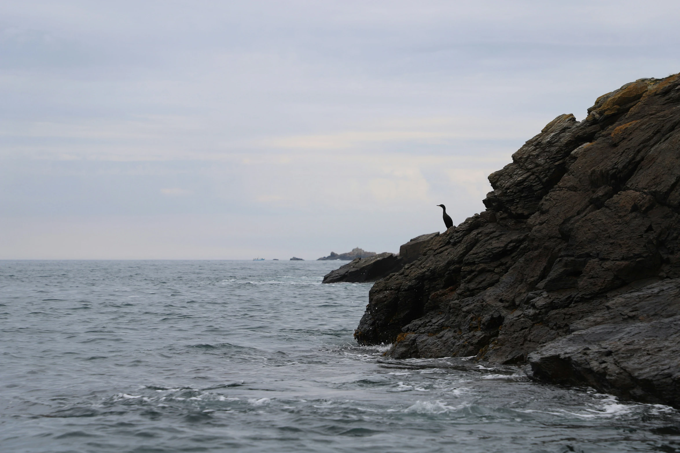 an ocean view with someone standing on rocks and holding their arms out to the water