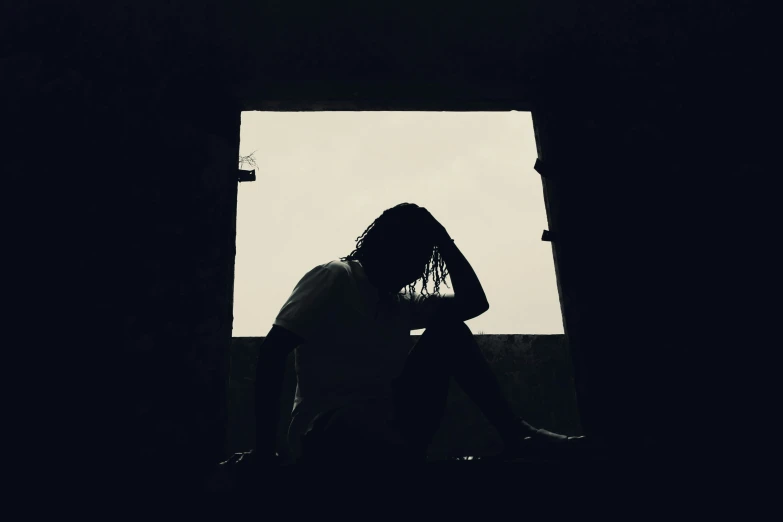 black and white image of person sitting on ledge outside of window