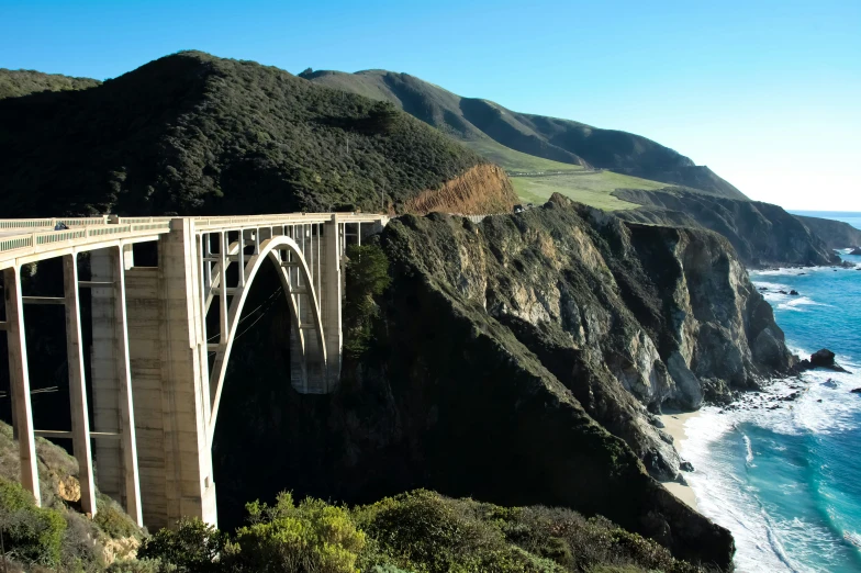 a bridge with an ocean and mountains in the background