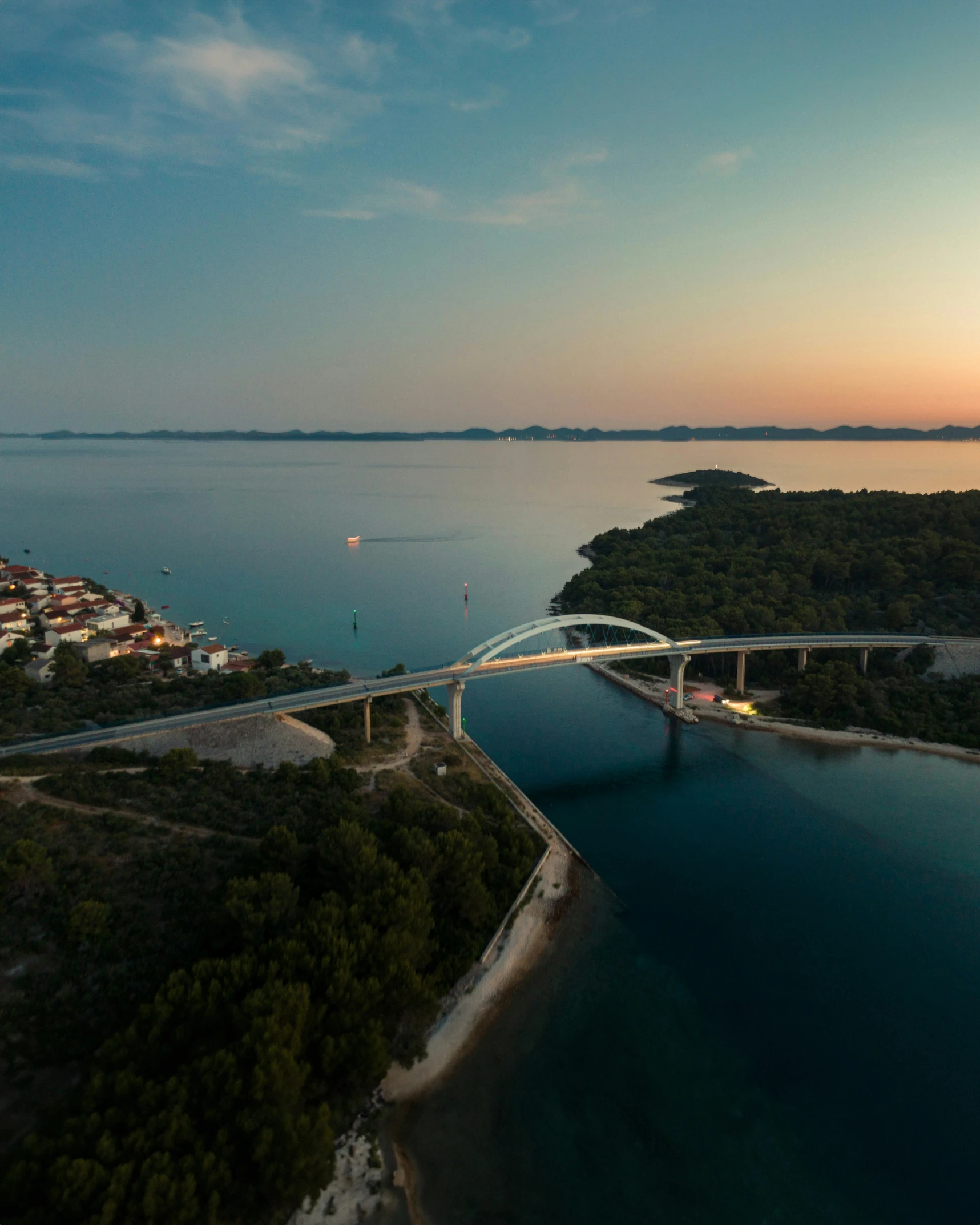 an aerial view of a highway bridge with a large body of water between two land