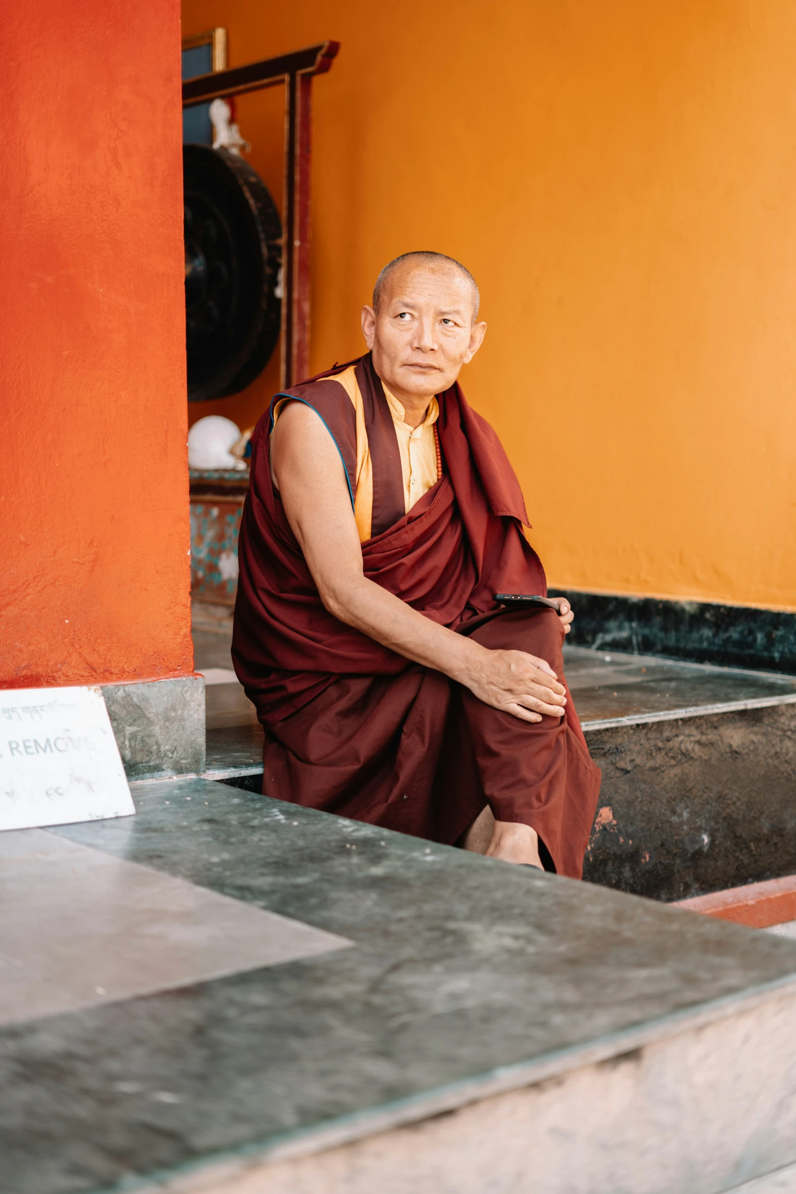 an old monk sits on some steps near a building