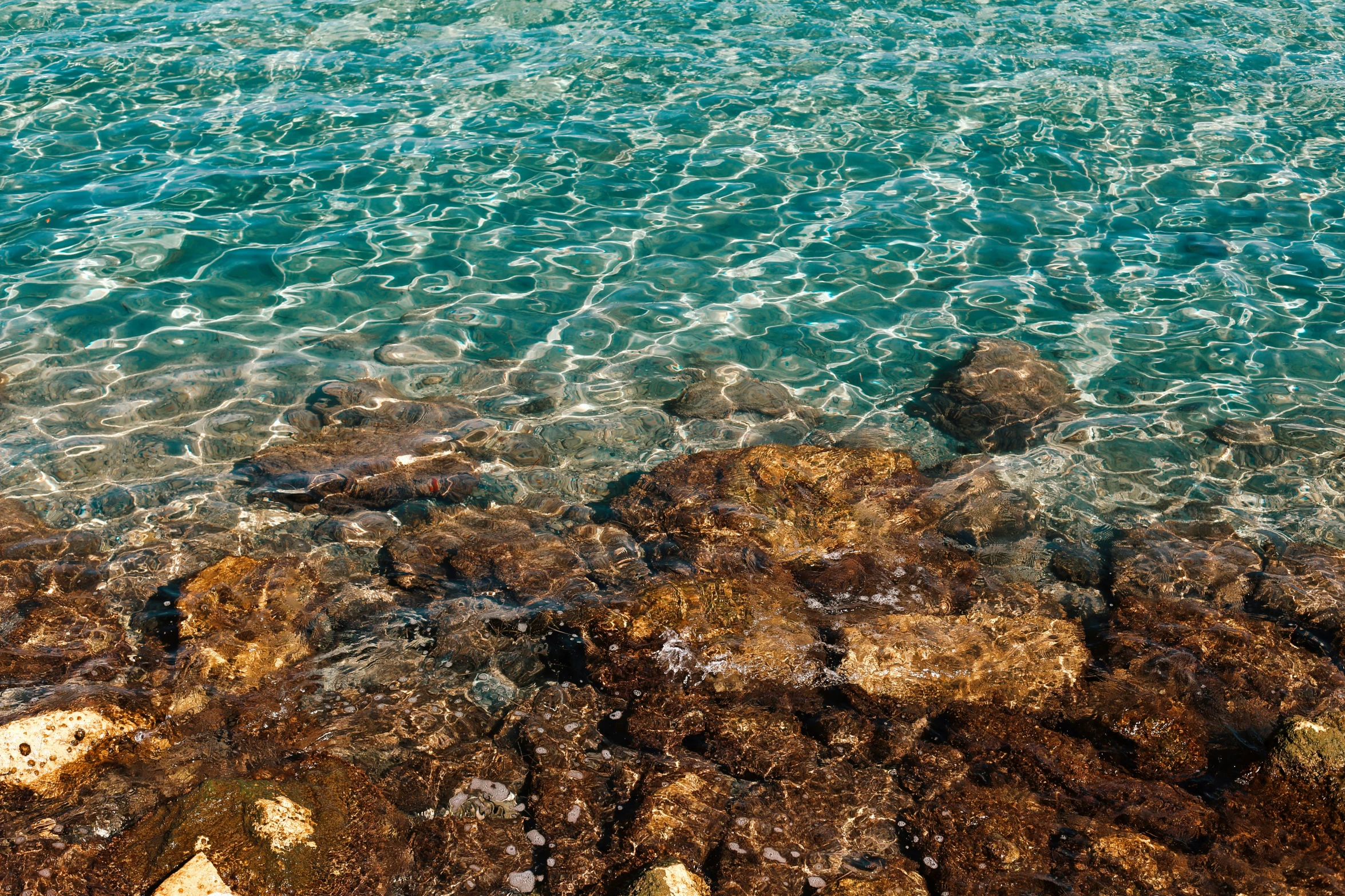 there is blue water and brown rocks in the sand