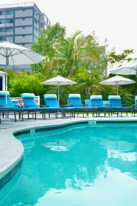 several lounge chairs in the sun near a swimming pool