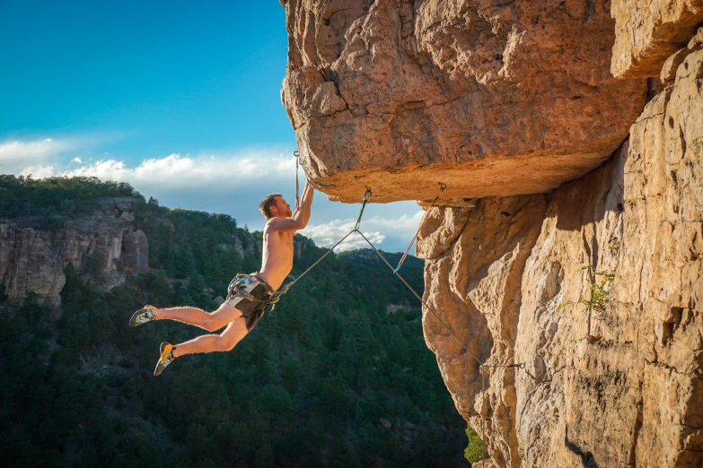 a man climbing along a high cliff on a rock face