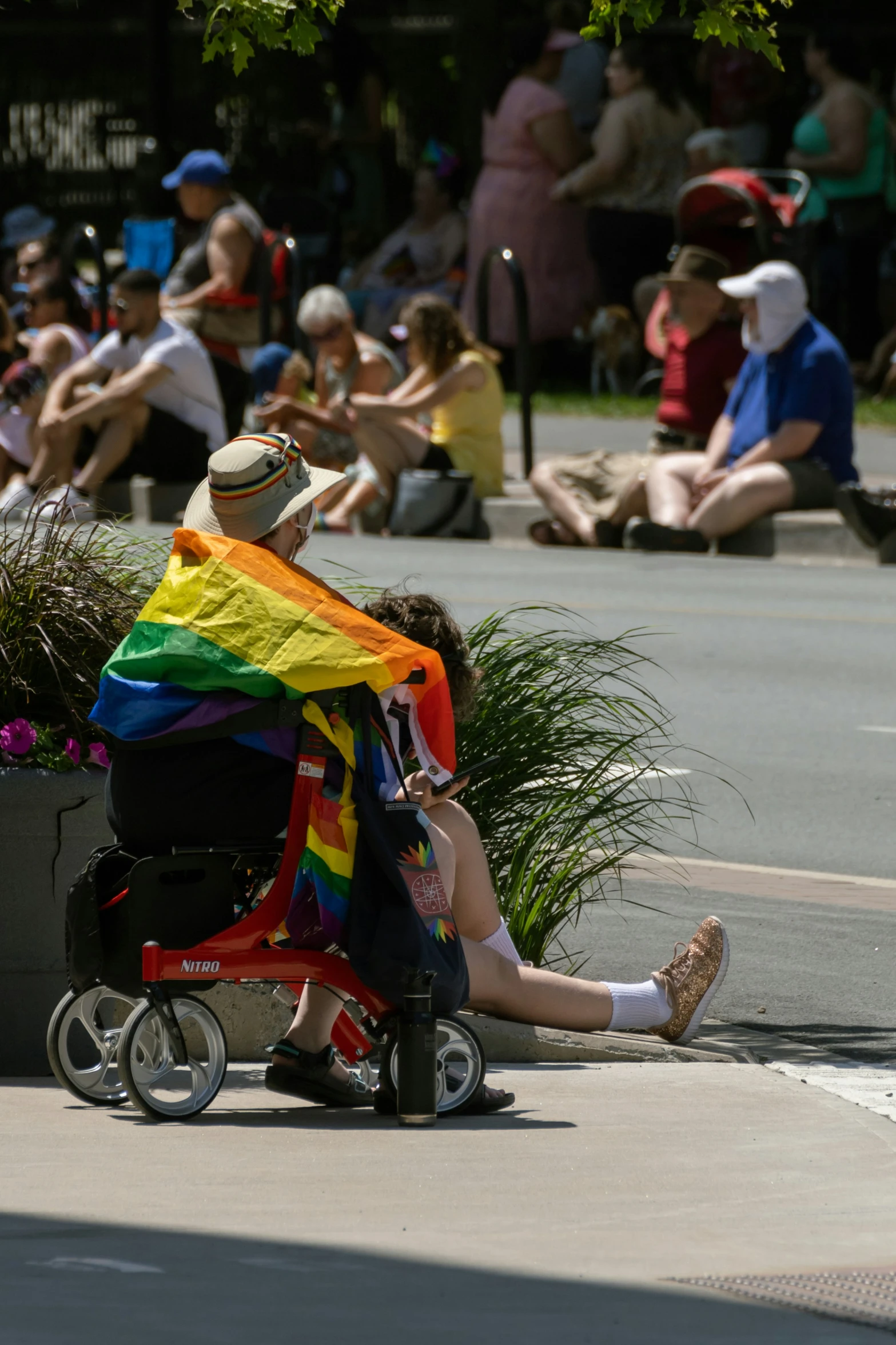 a man sitting on the sidewalk with a rainbow colored towel on