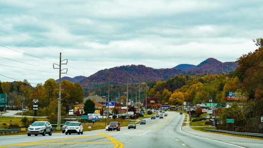 cars driving down an empty mountain highway in the fall