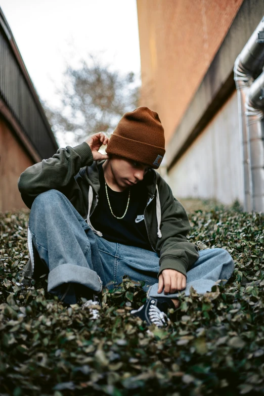 a boy in jeans and a hat sitting on the ground