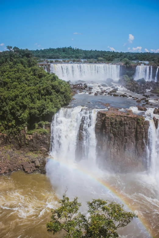 a waterfall with rainbow in it, as seen from the ground