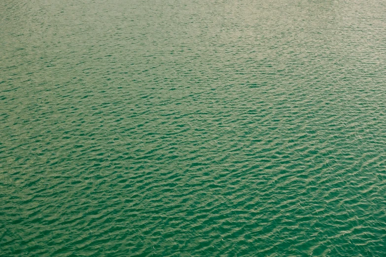 the water is green with some waves and dots on it