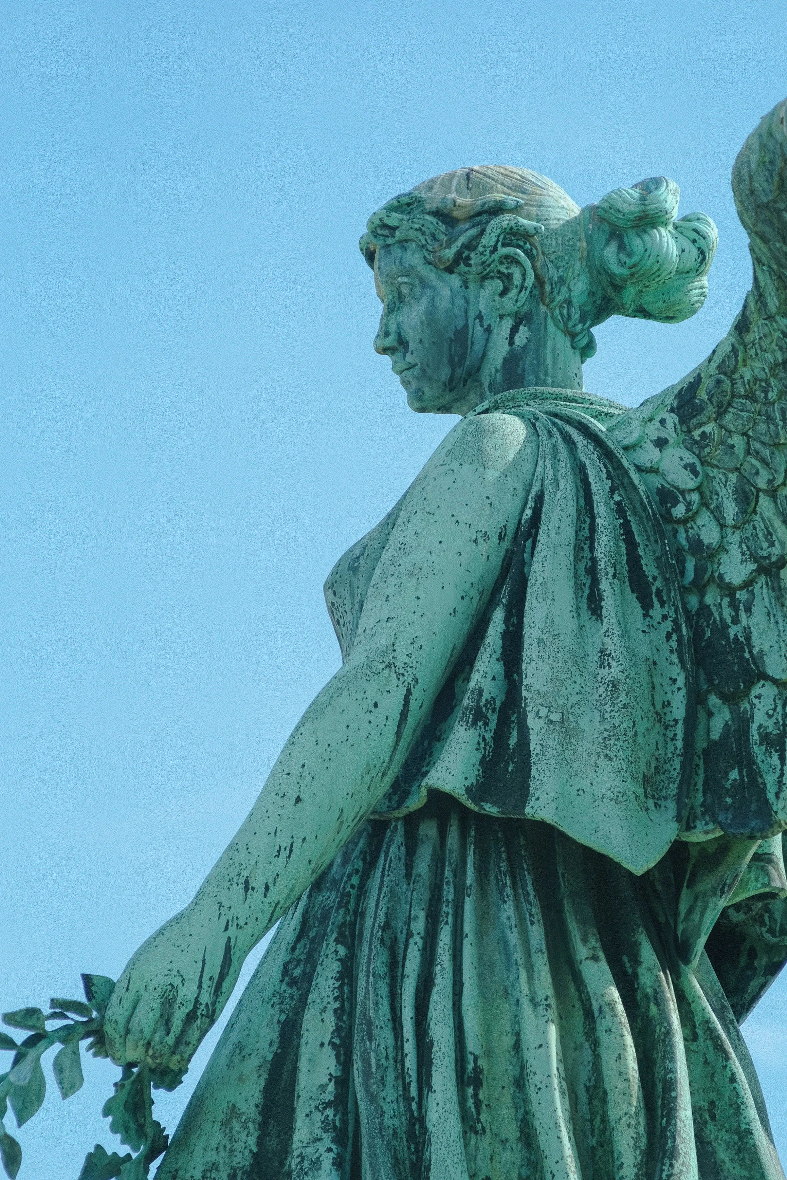 a green angel holding a nch of grass