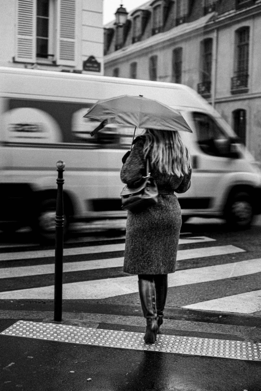 a woman walking on the street while holding an umbrella