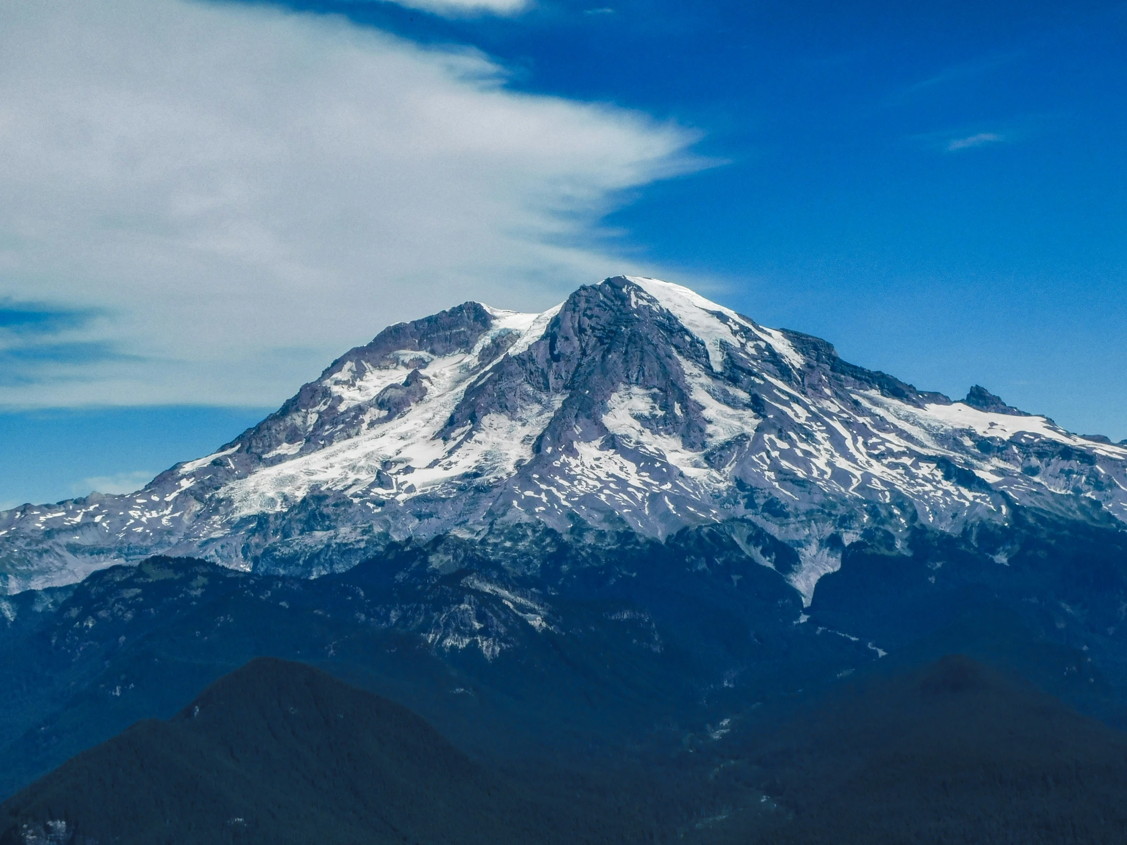 the mountains are covered with snow under a cloud filled sky