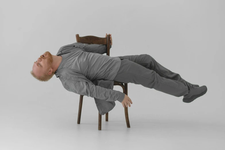 a man laying down on top of a wooden chair
