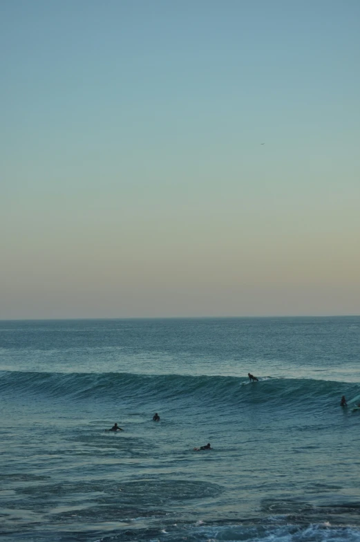 people are swimming in the ocean while one surfer catches a wave