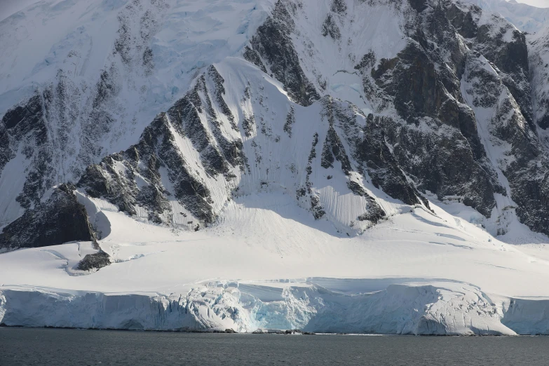 an iceberg floating in the water near large snow capped mountains