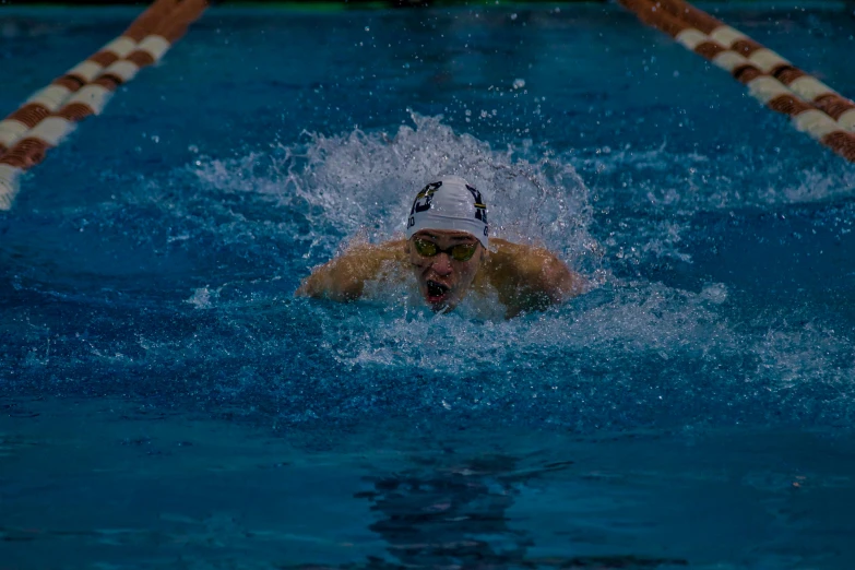 a person swimming in a pool near some chairs