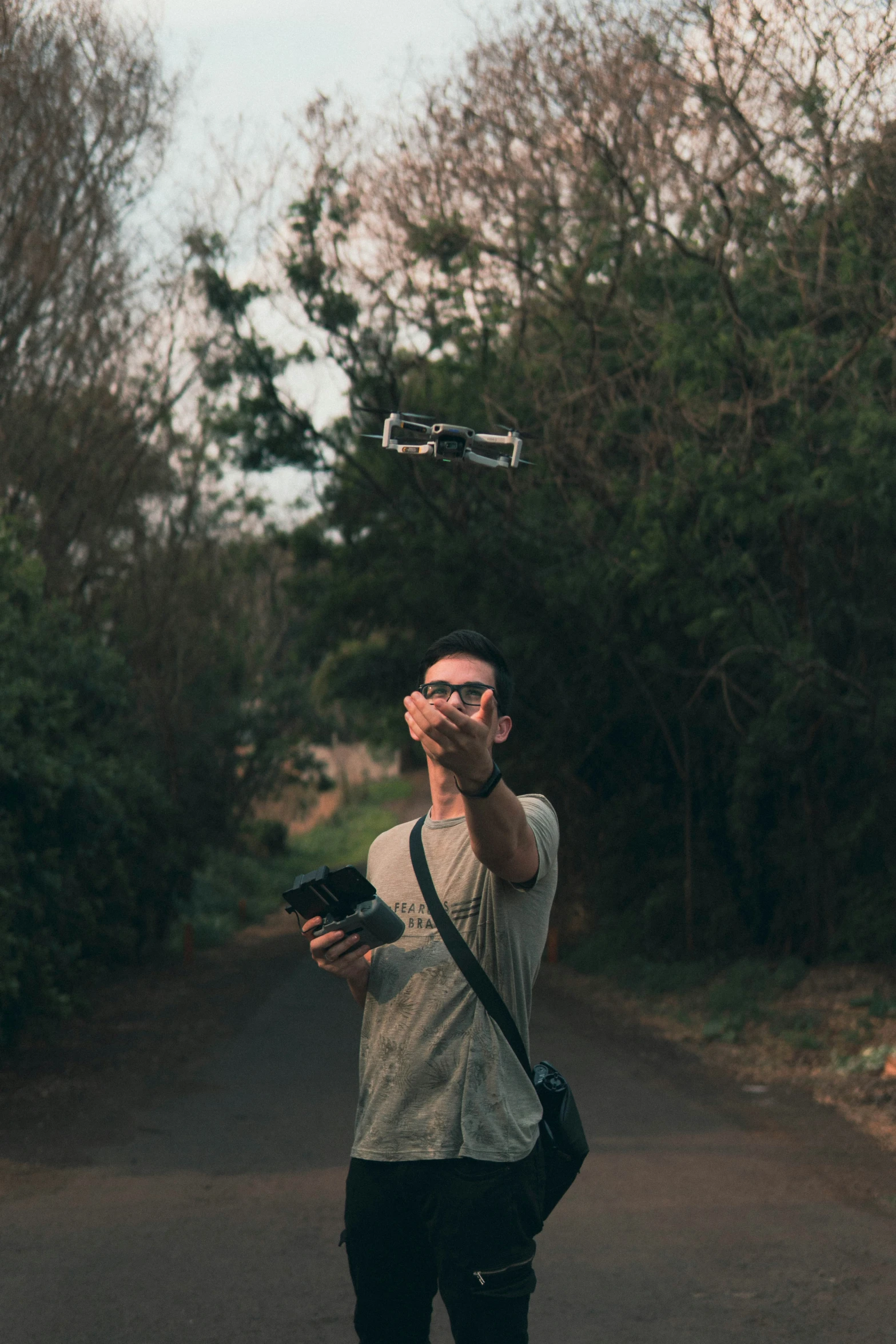 a man standing in the middle of the road holding a camera and flying a kite