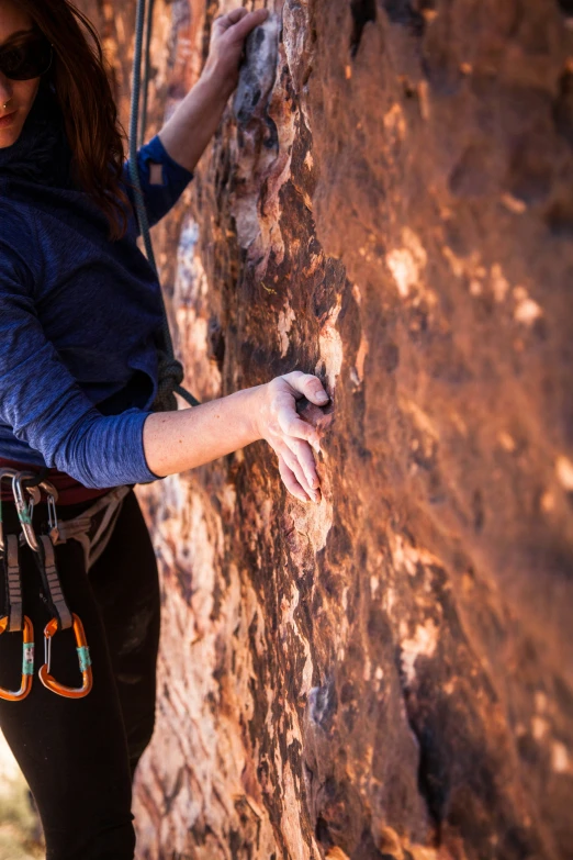 a woman standing next to a wall wearing a safety harness