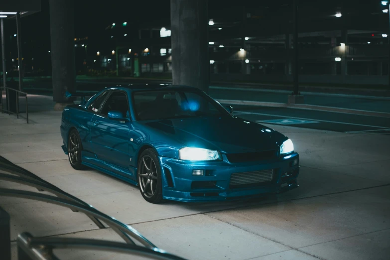 blue sports car parked near the curb at night