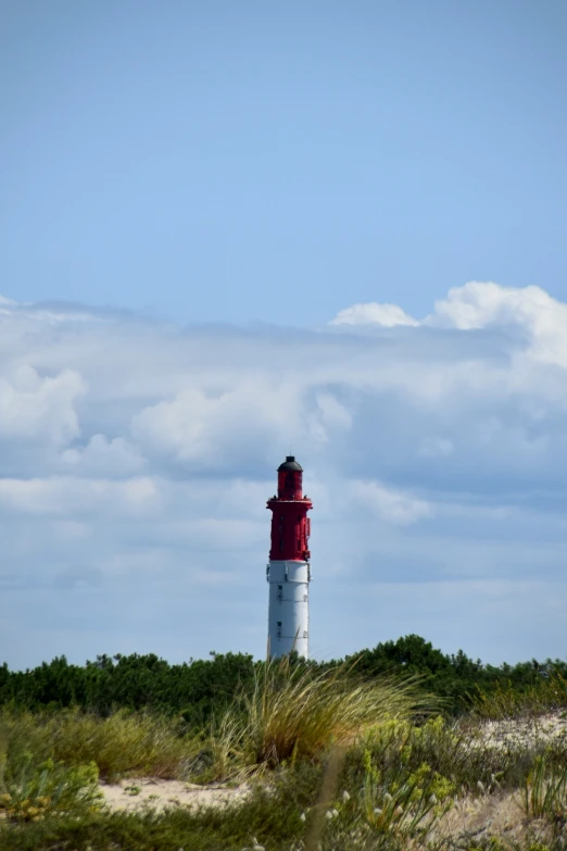 a lighthouse on the beach in front of a partly cloudy sky