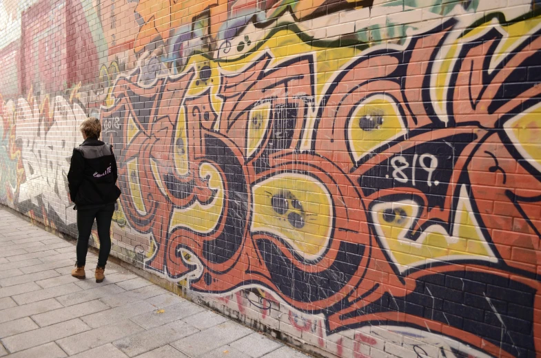 a woman standing near some wall graffiti with her back to the camera