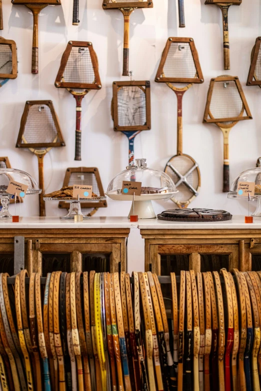 rows of rackets sit on shelves with hooks and mirror above them